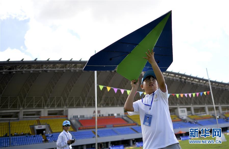 8月13日,江苏队小选手钱政言在遥控纸飞机穿龙门赛中帮队友投掷飞机.