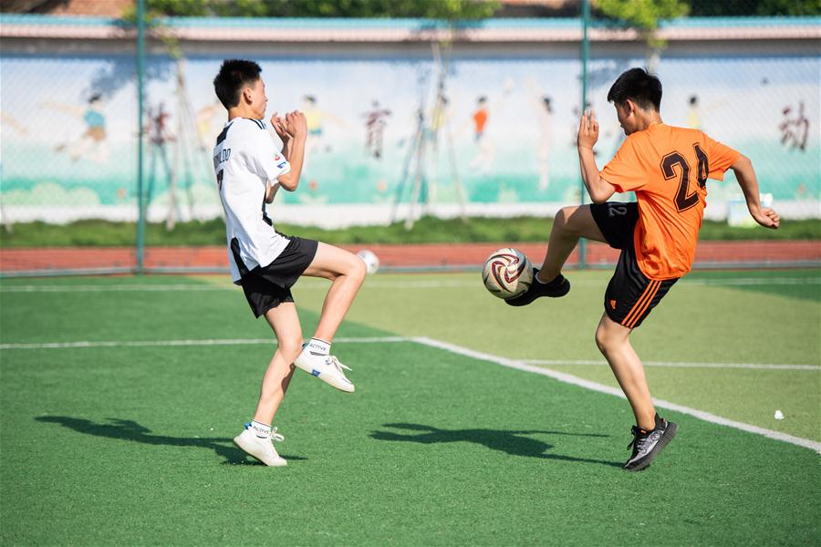  5月12日,学生们在体育课上进行足球训练.